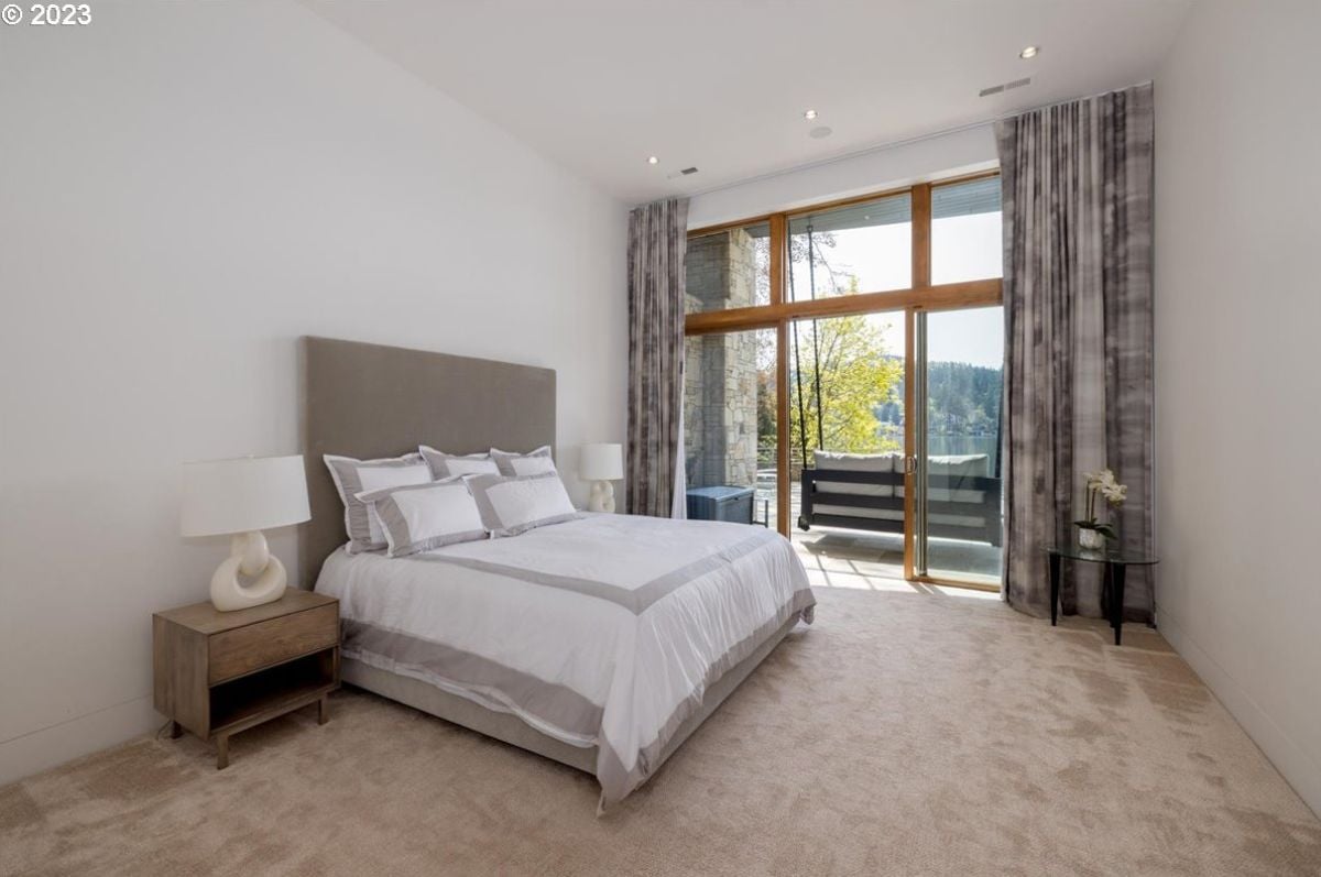 Bedroom with carpet flooring, a large bed and a balcony.