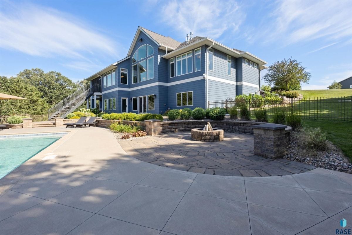 Rear view of the mansion with a pool and a fire pit.