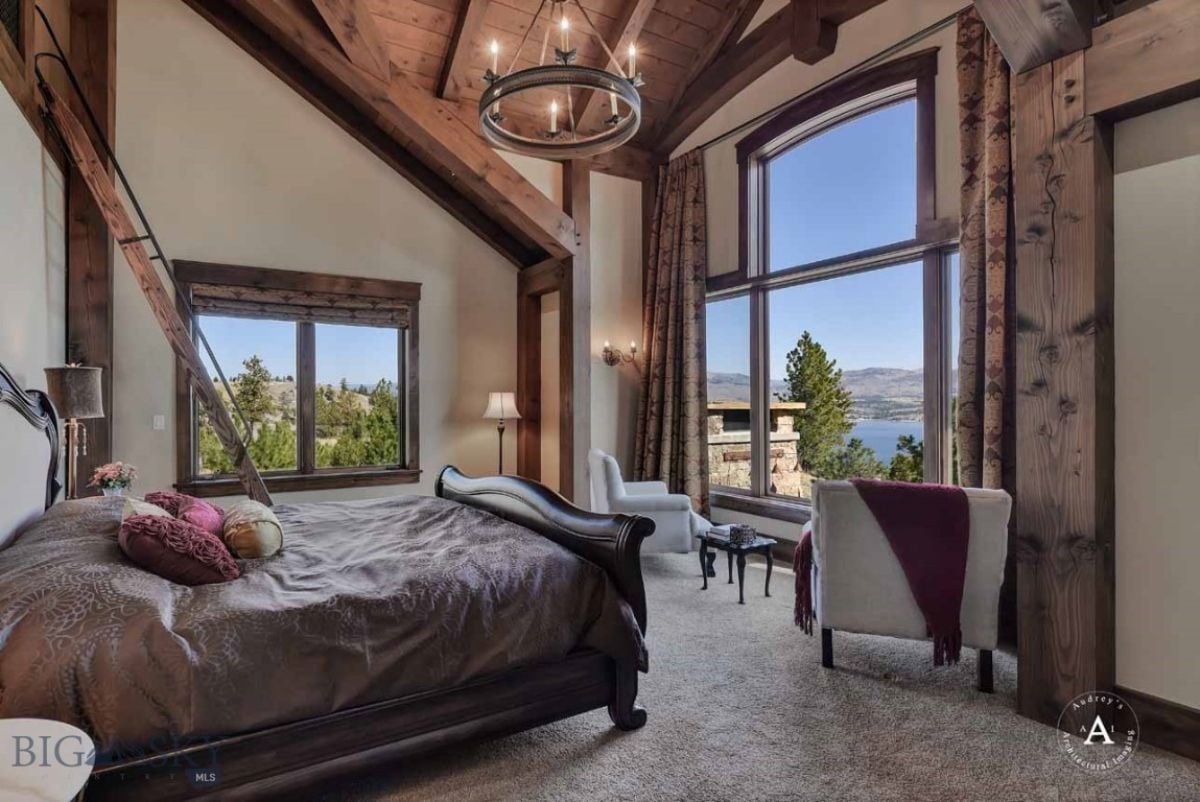 Bedroom with carpet flooring, a large bed and glass windows.