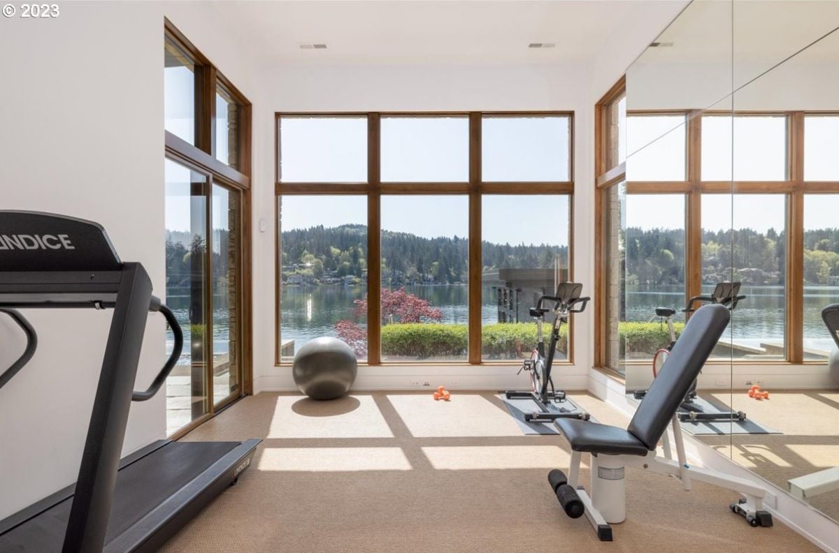 Home gym with carpet flooring, large glass windows and workout equipment.