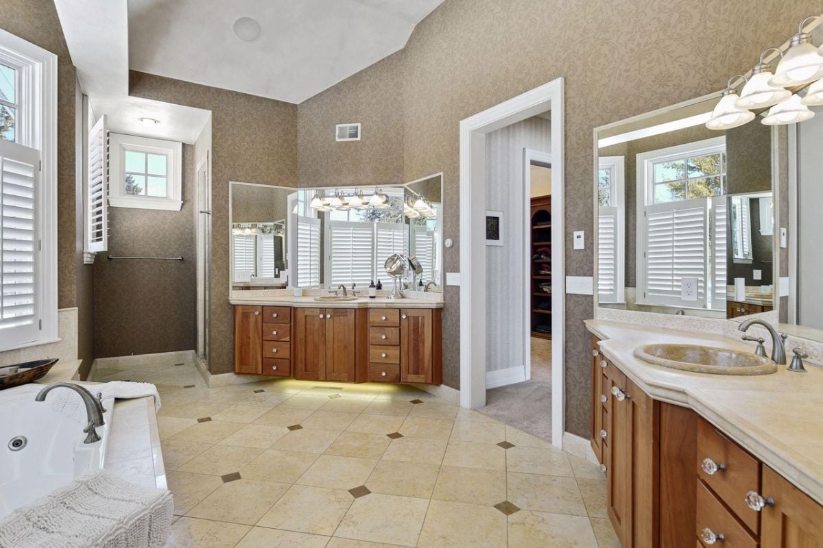Bathroom with sinks, large mirrors, tile flooring and a shower.