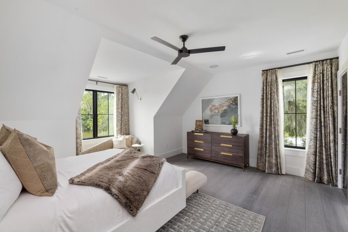 Bedroom with wood flooring, a drawer and a ceiling fan.