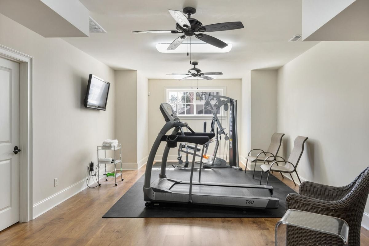 Home gym with a treadmill, a TV and a ceiling fan.