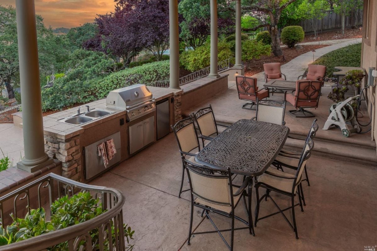 Covered patio with a grill, tables and chairs.