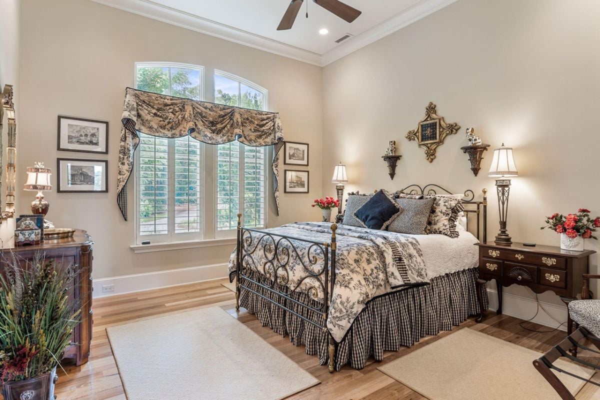 Bedroom with wood flooring, glass windows and a ceiling fan.
