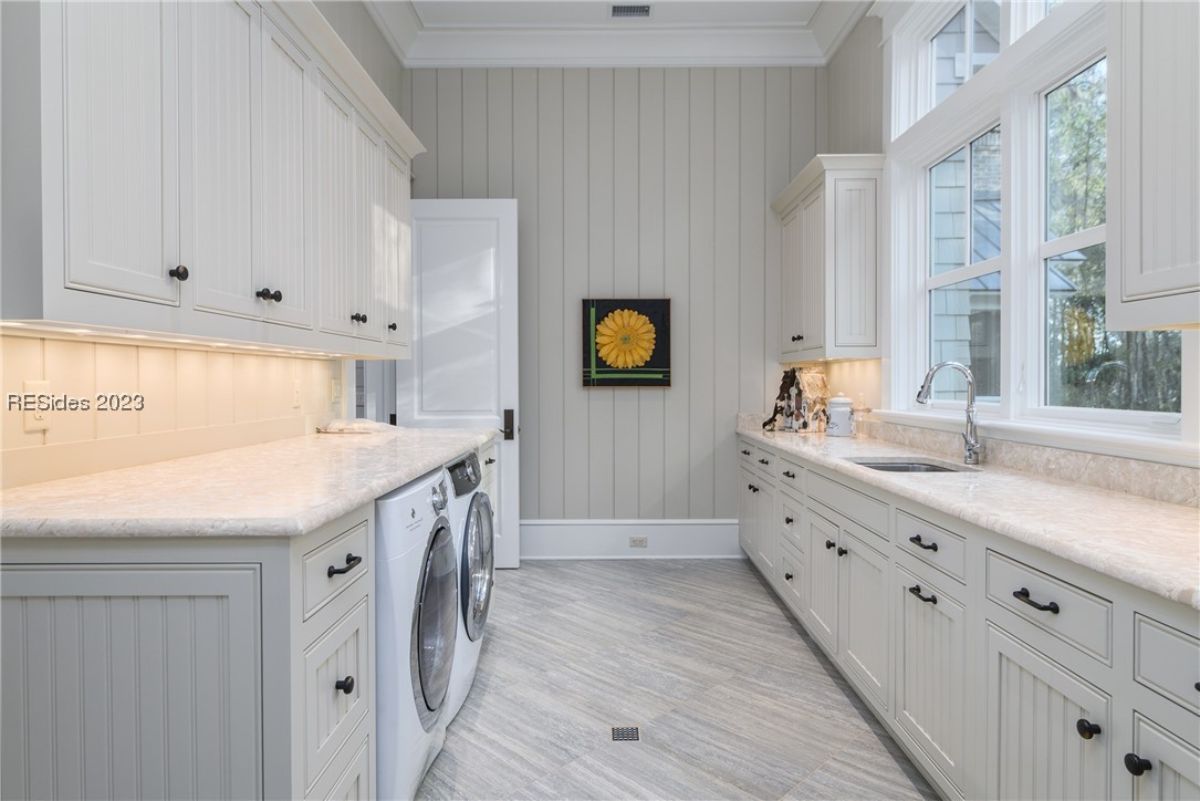 Laundry room with a sink, custom cabinetry, and glass windows.