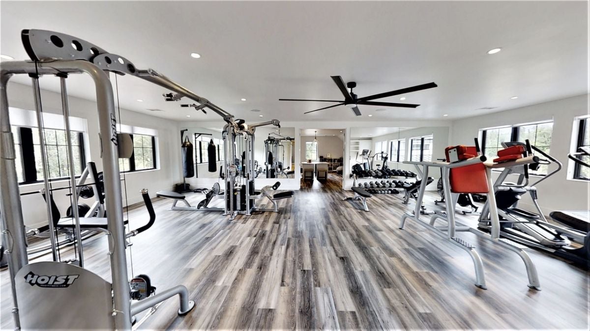 Home gym with a lot of workout equipment and a ceiling fan.