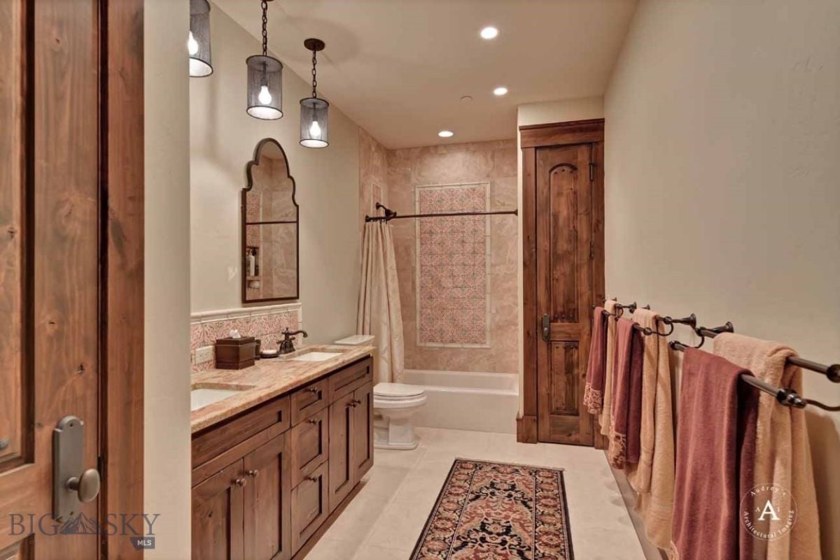 Bathroom with custom lighting, sinks, shower, and toilet