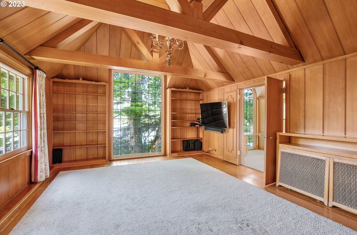 Media room with open beam ceiling, a TV and glass windows.
