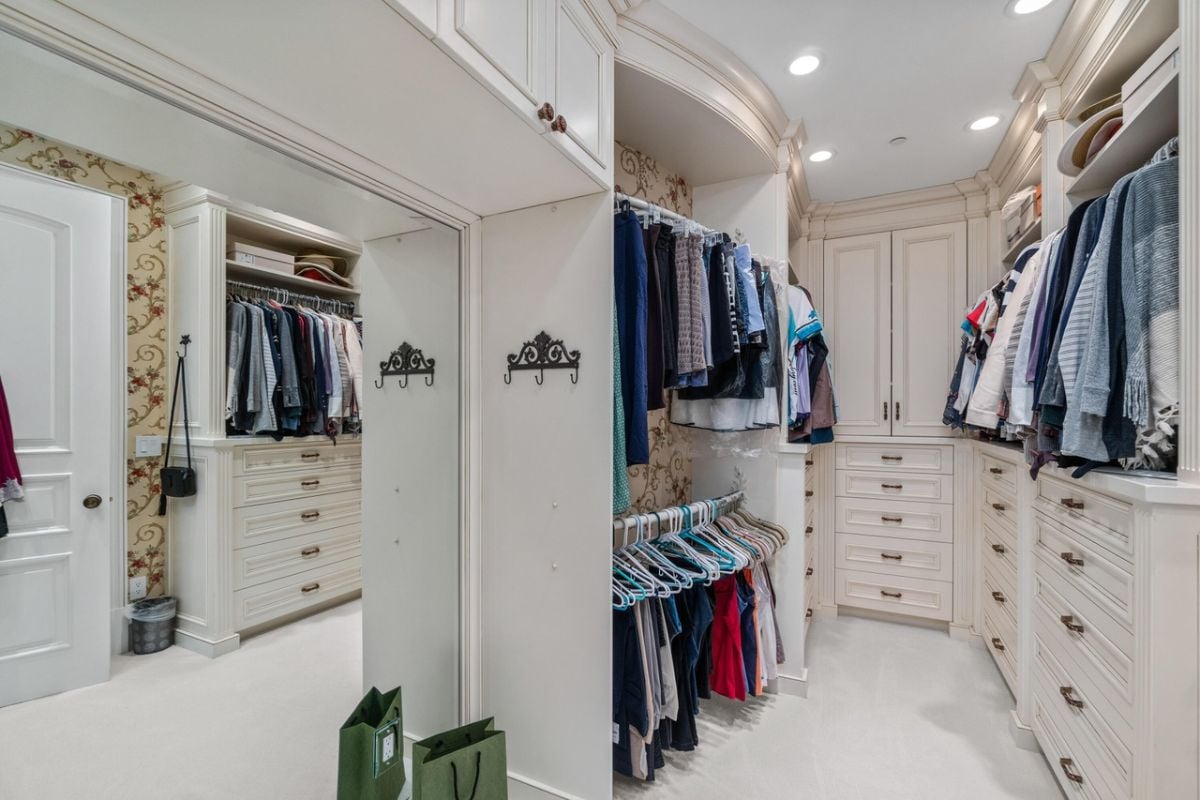 Walk-in closet with white cabinets and drawers.