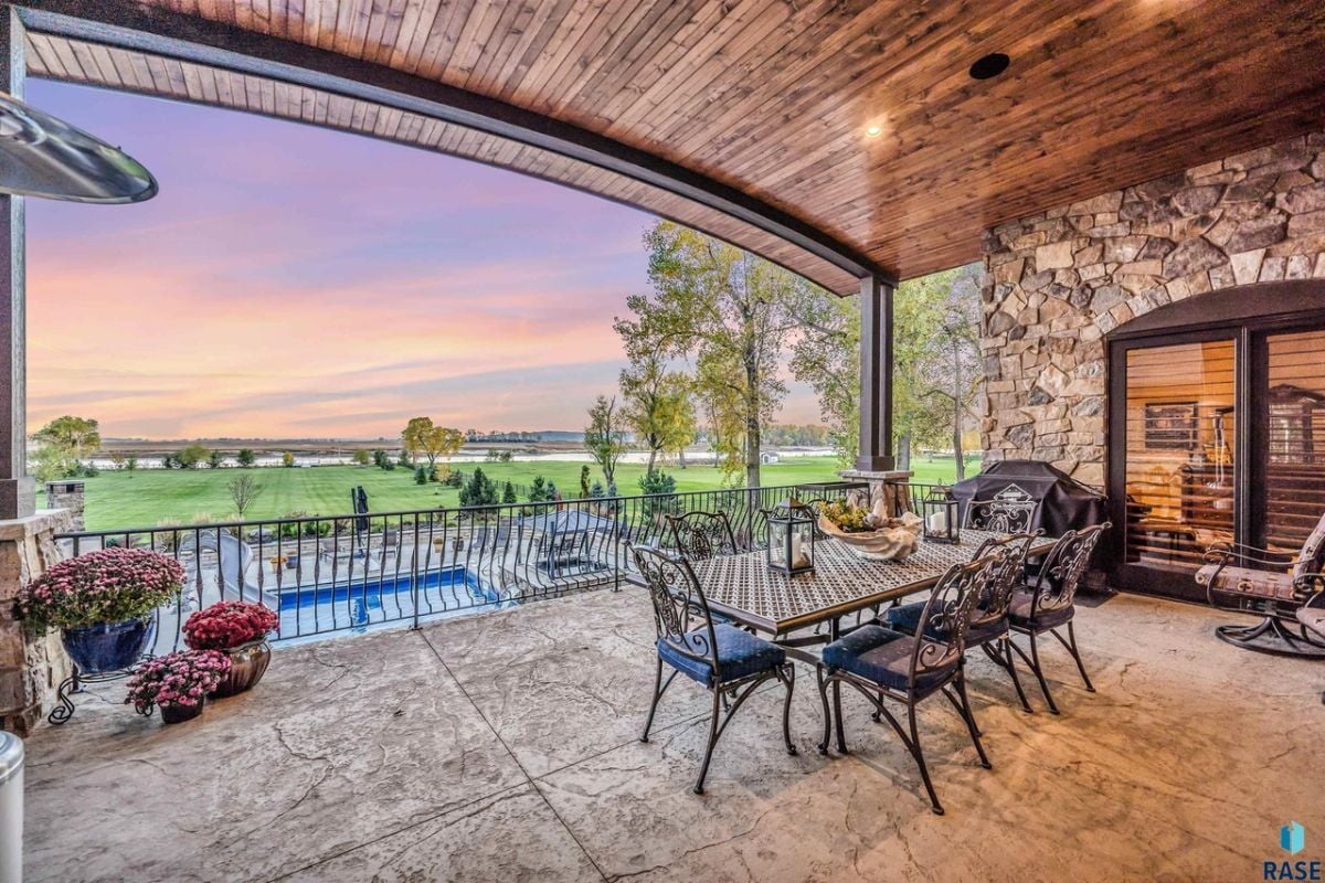 Balcony with table, chairs and a view of the pool and backyard lawn.