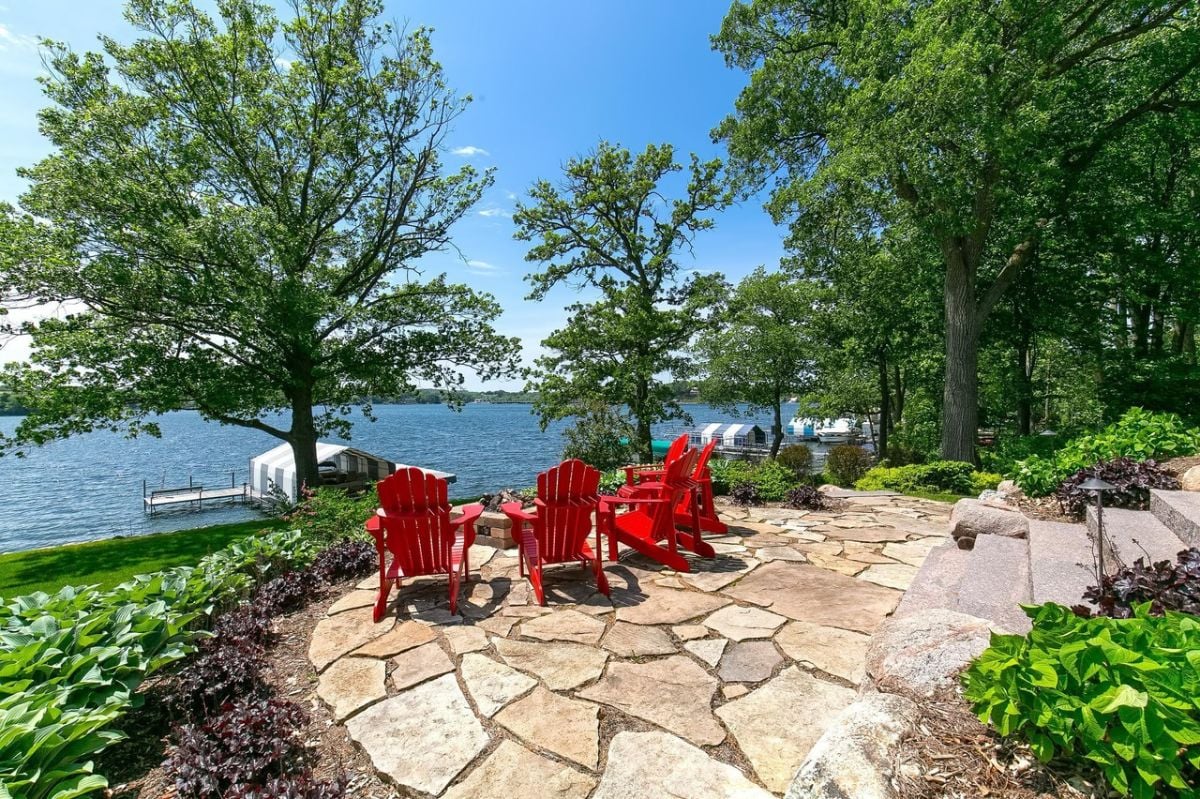 Patio with red chairs and a lake view.