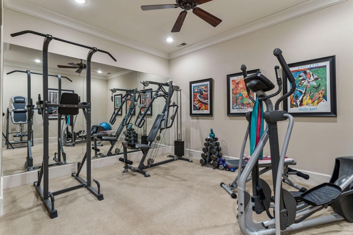 Home gym with carpet flooring and a large mirror.