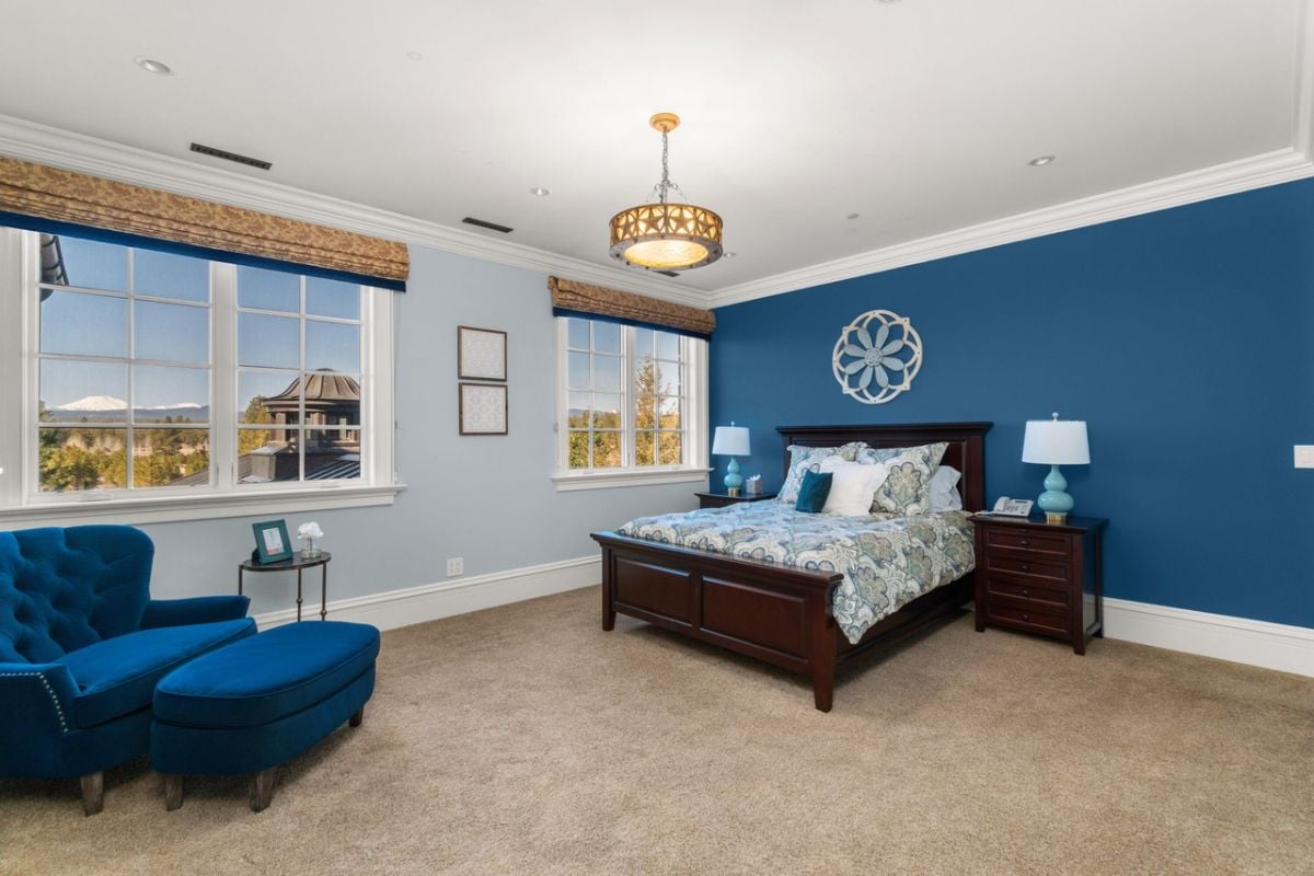 Bedroom with carpet flooring, glass windows, a couch and a large bed.