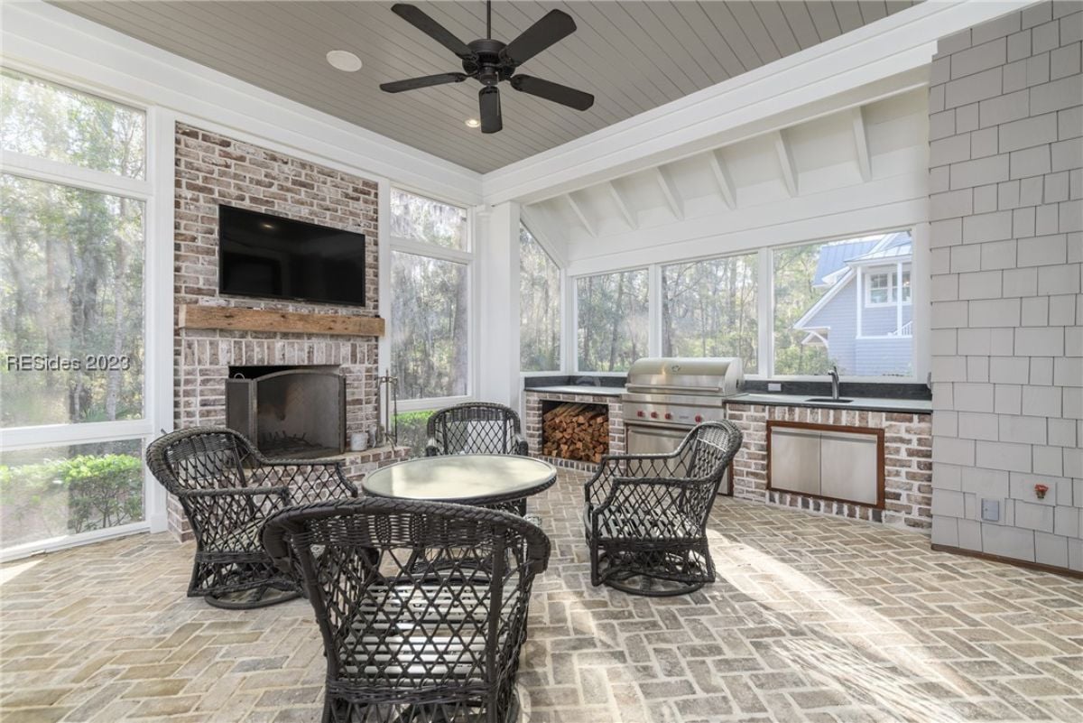 Screened patio with a fireplace, grill and a television.