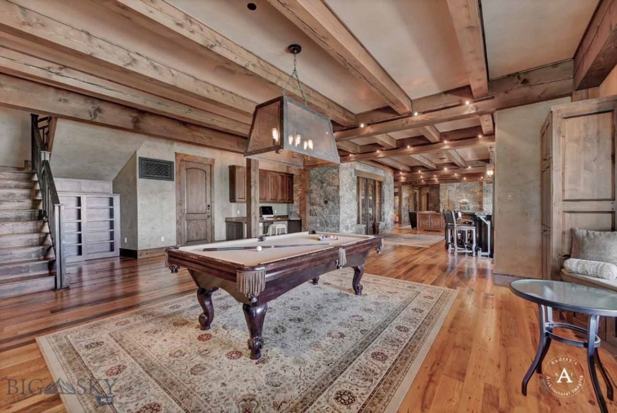 Billiards room with open beam ceiling, wood flooring and a chandelier.