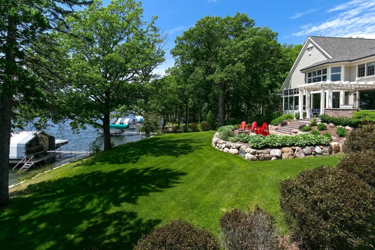 Backyard of the house with a green lawn near the lake.