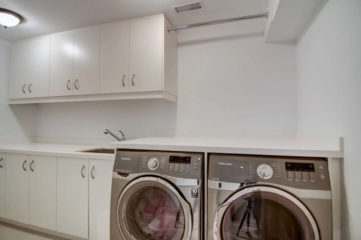 Laundry room with a washer, dryer, a sink and white cabinets.