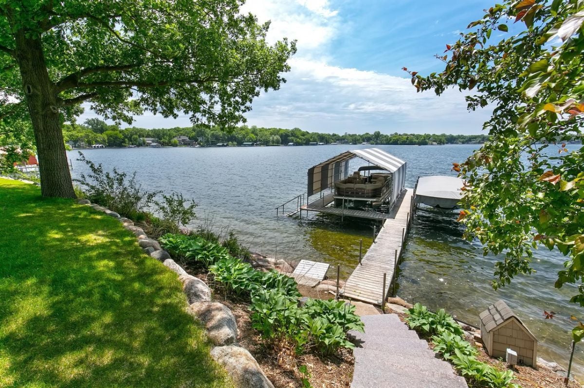 Dock sits on the shore of a lake with a boat.