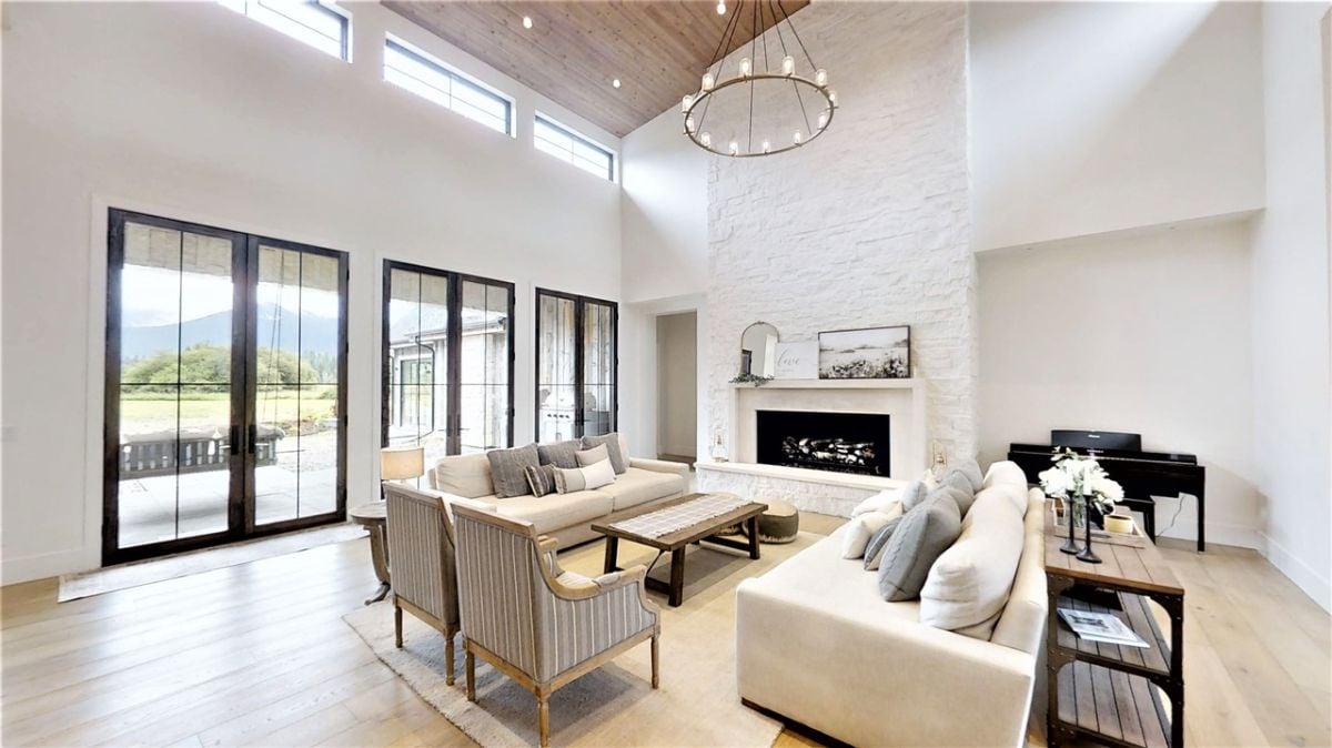 Modern living room with couches, large glass doors and a fireplace.