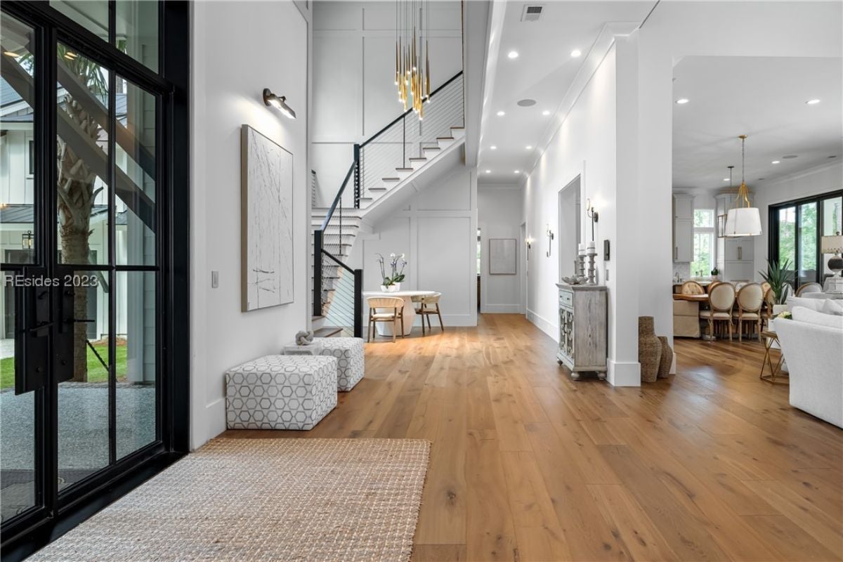 Foyer with glass doors, wood flooring and a a staircase.