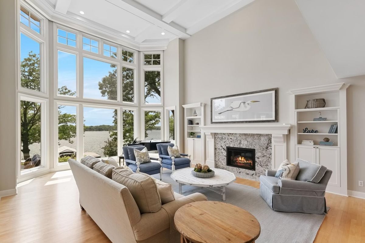 Living room with wood flooring, couches, fireplace, and huge glass windows.
