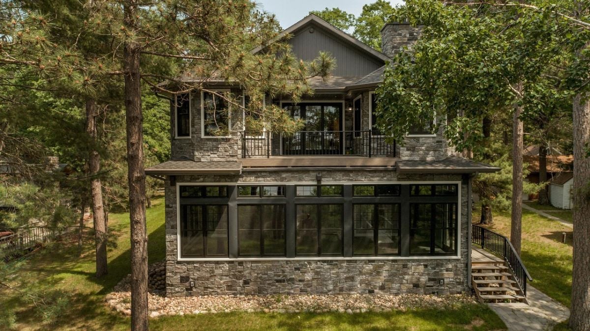Rear view of the house with a stone wall and a balcony.