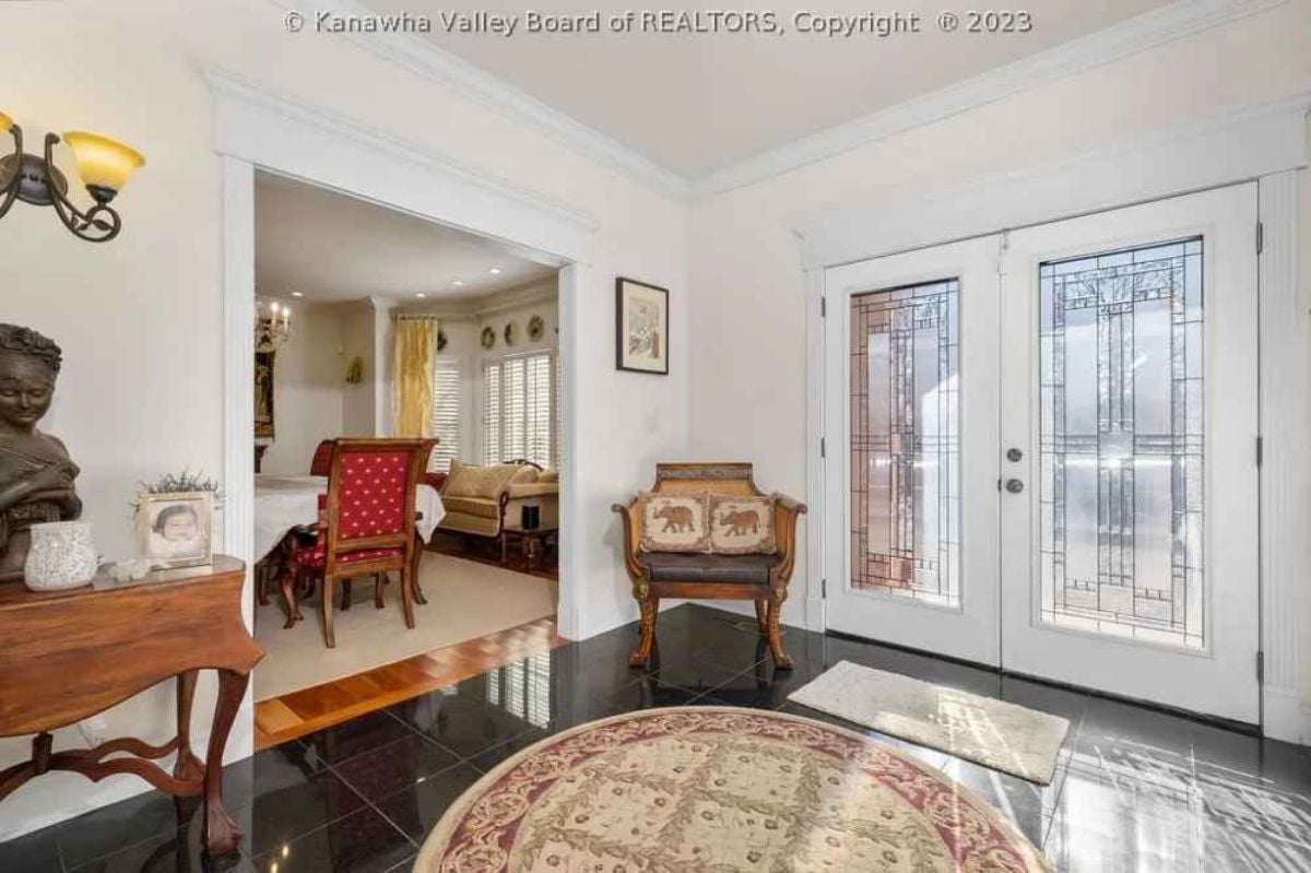 Foyer with a large wooden/glass door, a rug, and a chair.