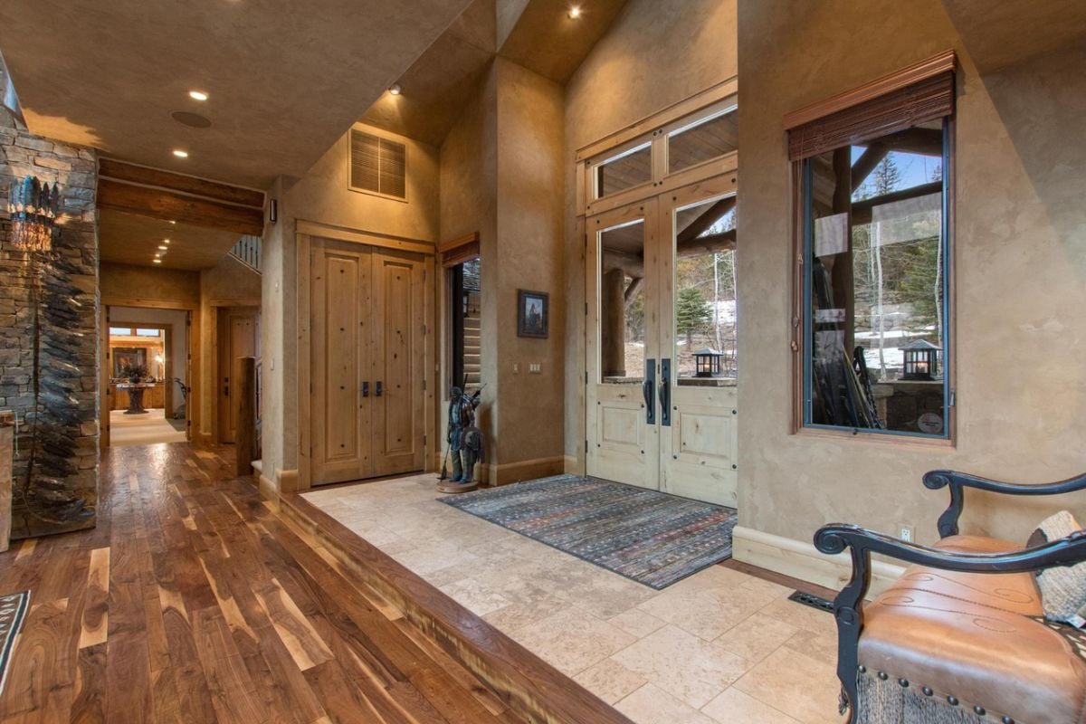 Large foyer with a rug, tile and wooden floor.
