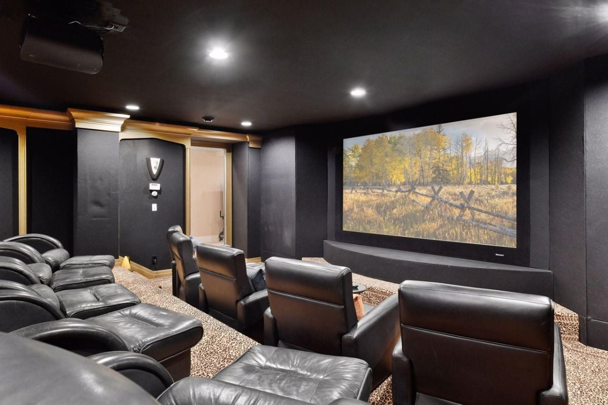 Home theater with leather couches and a huge flat screen.