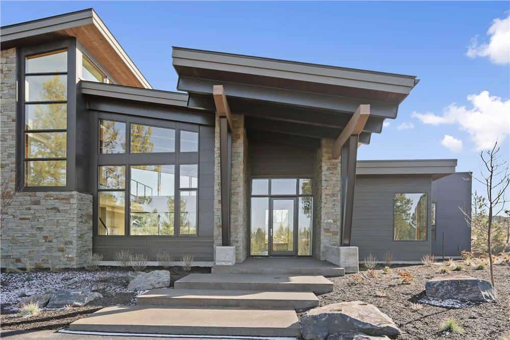 Front entry with a sloped roof, a stone walkway and a glazed front door surrounded by sidelights and transoms.
