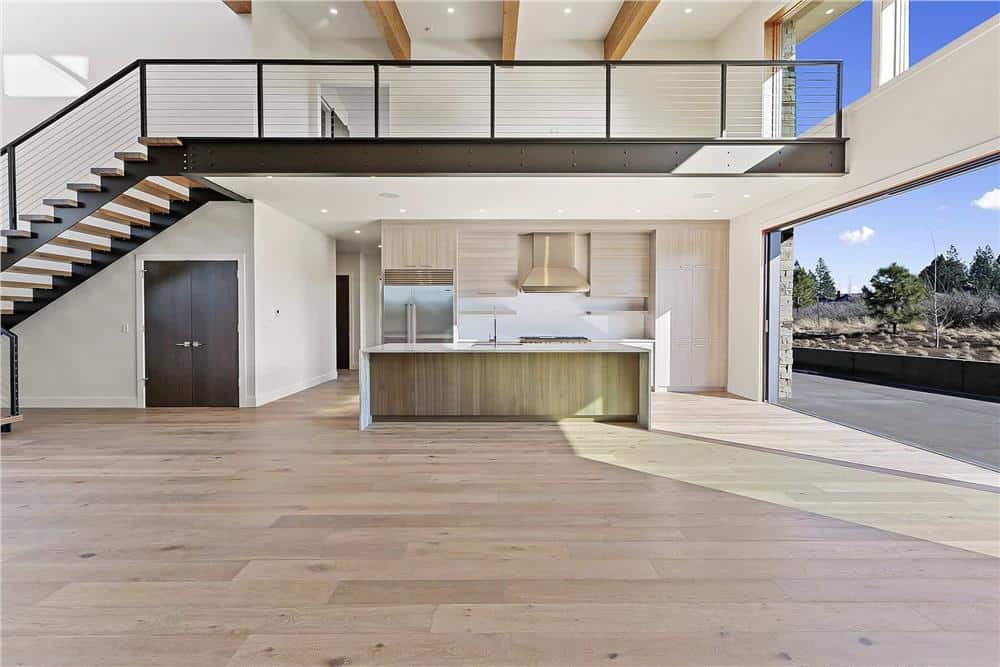 Great room and kitchen with hardwood flooring and a tall beamed ceiling.