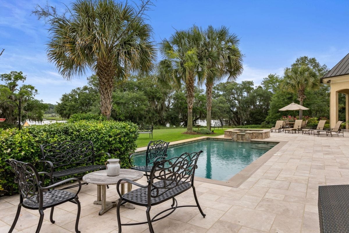 Pool with lounge chairs and a large backyard lawn.