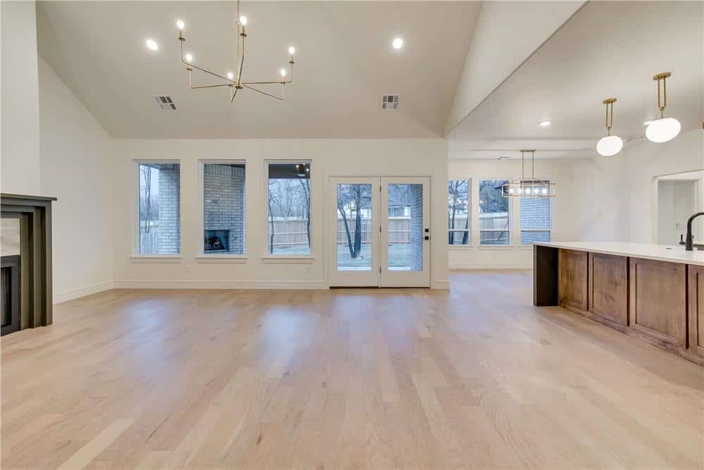Great room and kitchen with light hardwood flooring and a glazed door that opens to a covered porch.