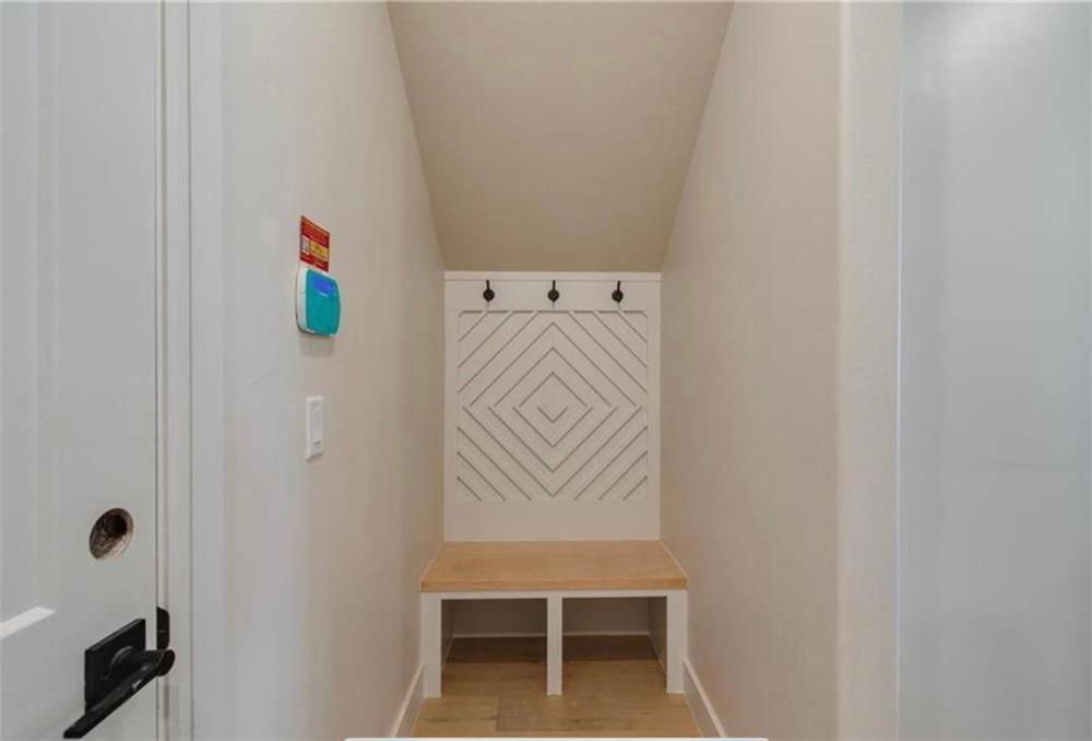 Mudroom with coat hooks and a built-in bench under a low vaulted ceiling.