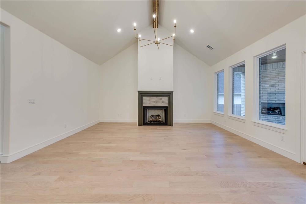 Great room with a fireplace and a cathedral ceiling lined with an exposed beam.