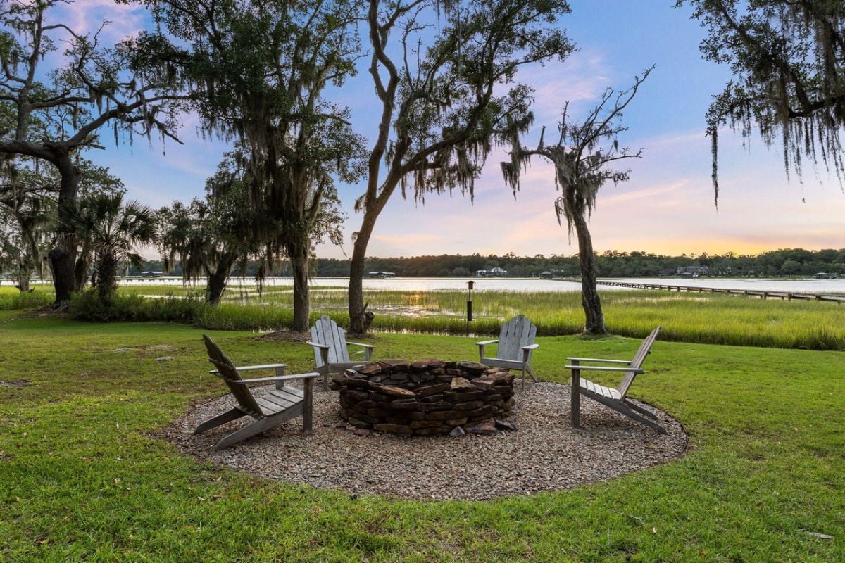 Fire pit with chairs in the backyard lawn.