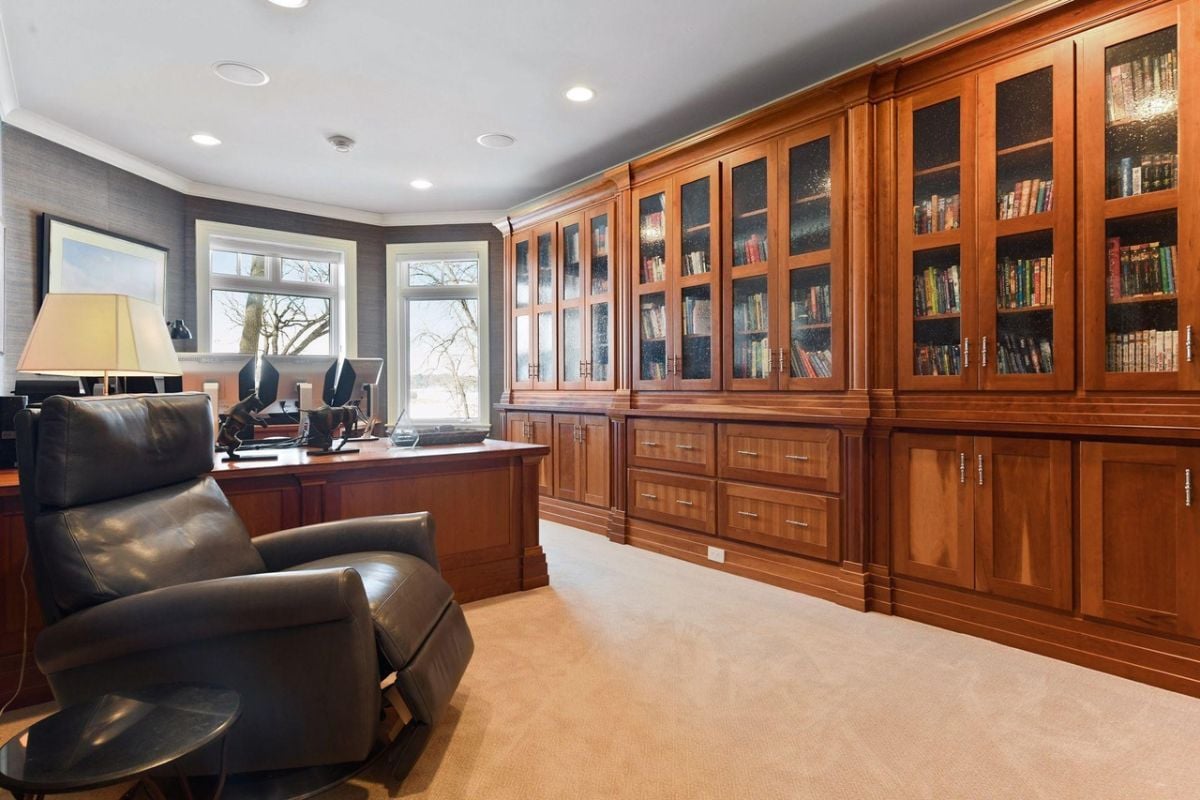 Home office with a large desk, carpet flooring and custom cabinetry.