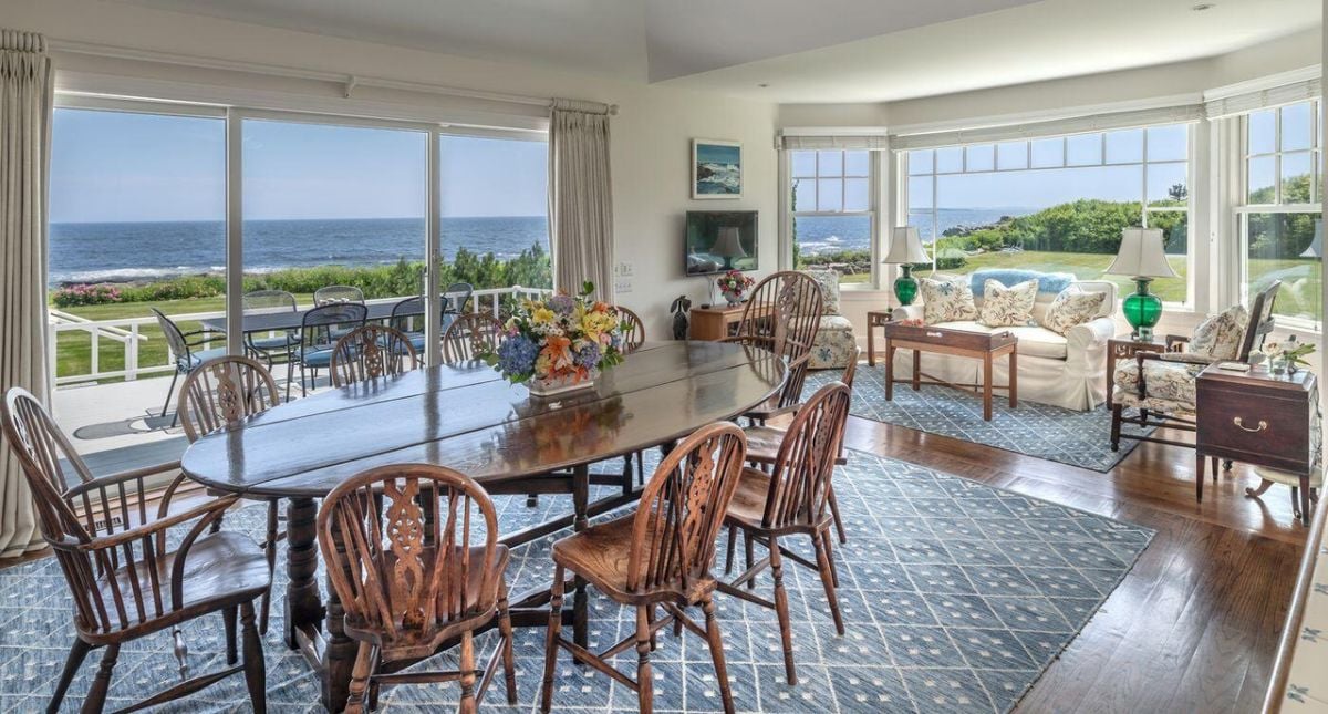 Dining room with a large table, chairs and a view of the ocean.