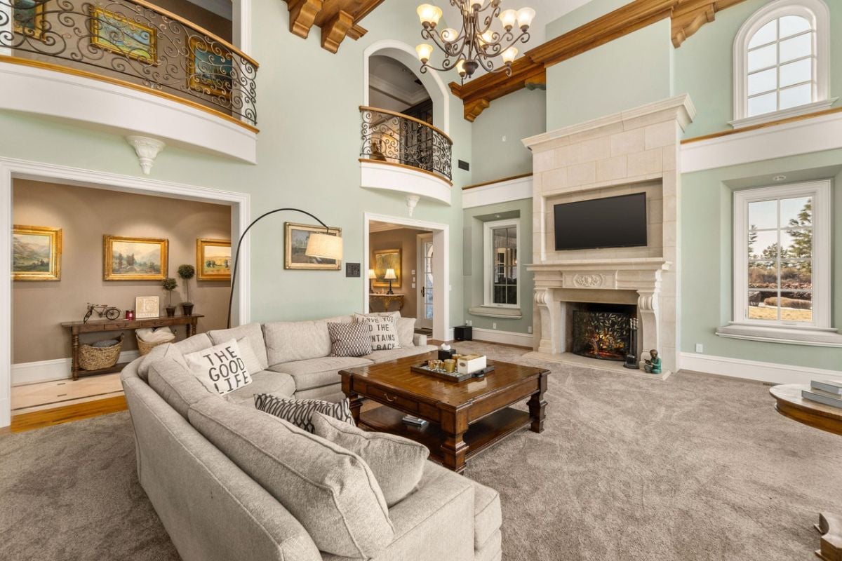 Living room with carpet flooring, a chandelier and a fireplace.