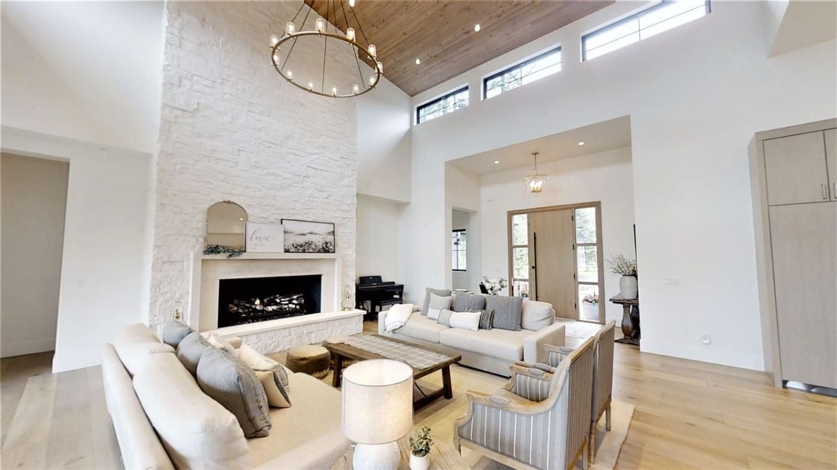 Modern living room with couches, wood flooring and a fireplace.