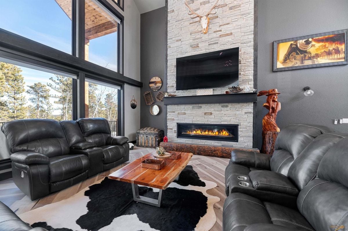 Living room with couches, a TV, fireplace, and glass windows.