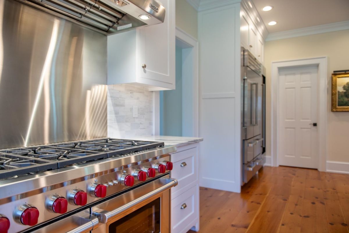 Kitchen with a stove, wood flooring and custom lighting.