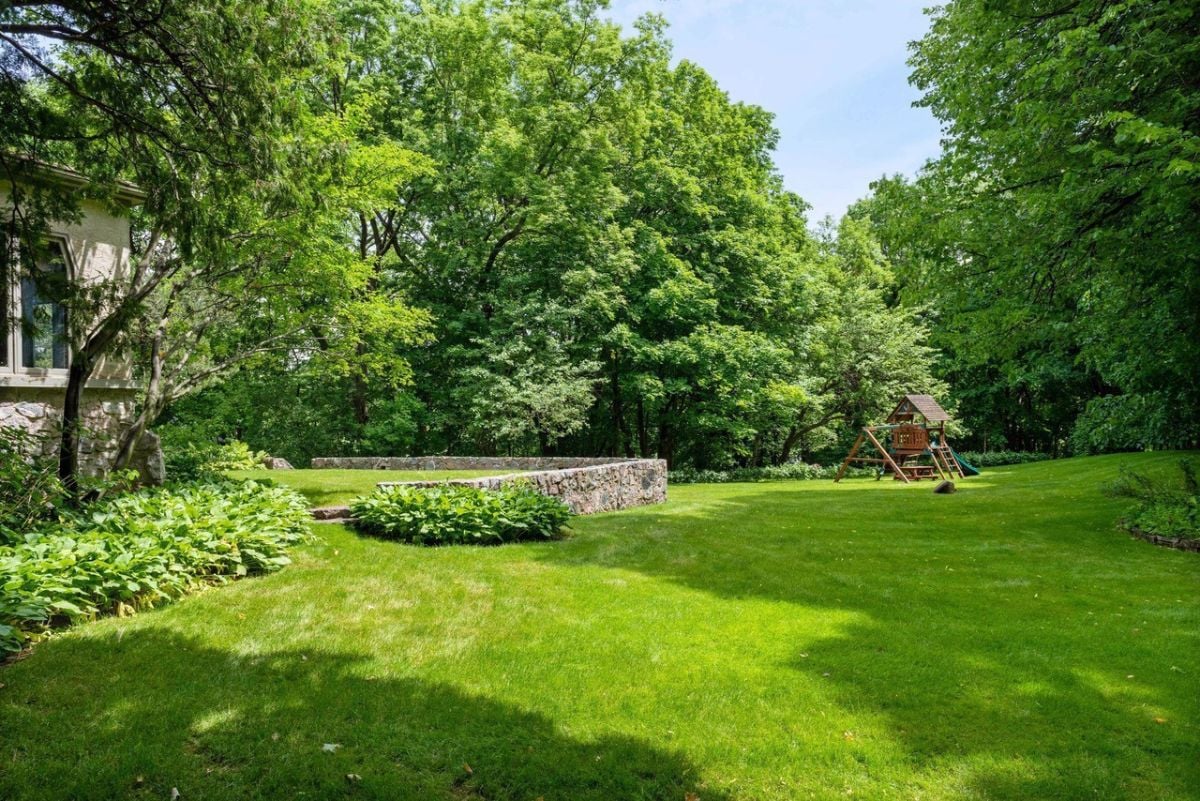 Backyard of the mansion with green lawn and trees.