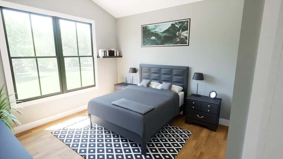 Secondary bedroom with a gray bed over a patterned rug and a large window that looks out the front yard.
