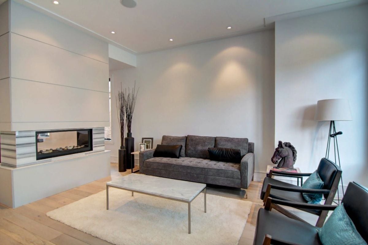 Living room with couches, wood flooring and a fireplace.