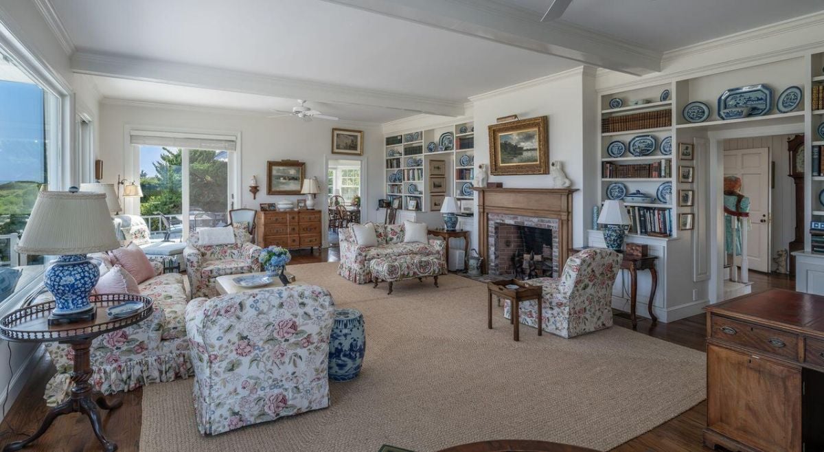 Living room of the house with couches, glass windows, and a fireplace.