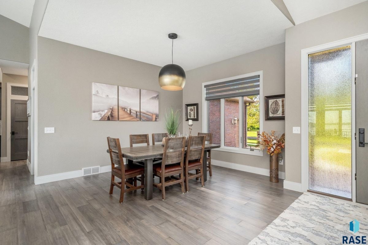 Dining room with wood flooring, a wooden table and chairs.