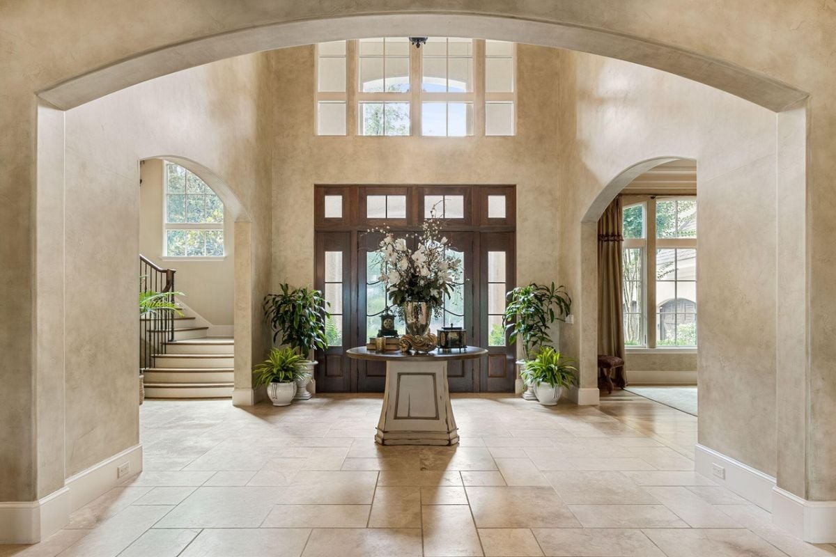 Foyer with tile flooring, wooden door and staircase leading to the second level.