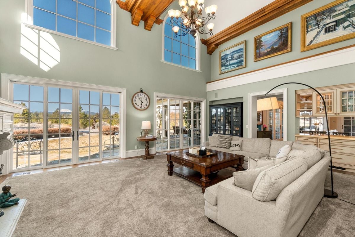 Living room with carpet flooring, a chandelier and large glass doors..